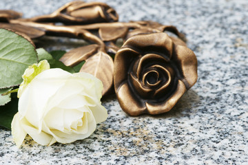 Rose aus Bronze und weiße Rose auf Grabplatte, copy space