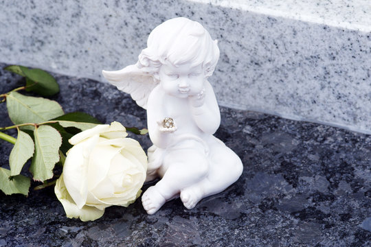 Engel und weiße Rose auf Grab