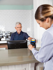 Woman Making Payment Through Mobilephone At Counter