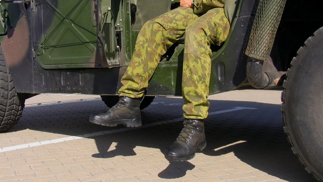 Relaxed soldier sitting in his military vehicle