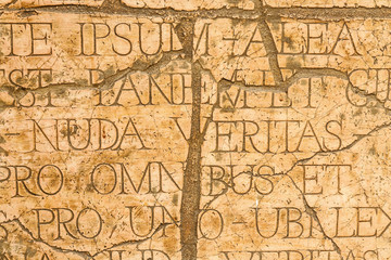 Fototapeta na wymiar Pęknięty mur z łacińskimi inskrypcjami i literami rzymskimi