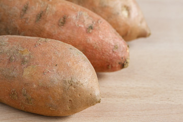 Three sweet potatoes on a wooden chopping board
