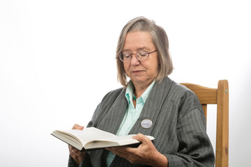 Alte Frau im Stuhl liest im Buch