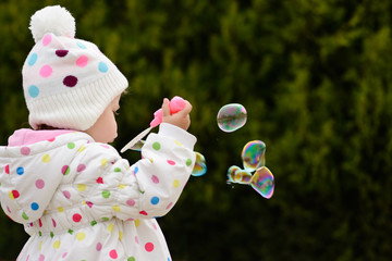 toddler girl blowing soap bubbles