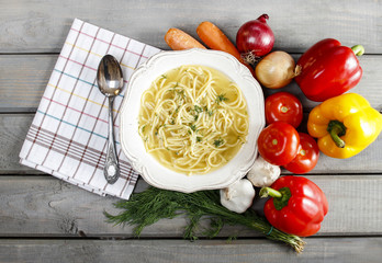 Top view of broth in white bowl on grey rustic wooden table