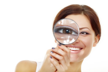 Smiling attractive woman looking through a magnifying glass over
