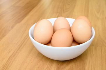 Eggs in white bowl on wooden table