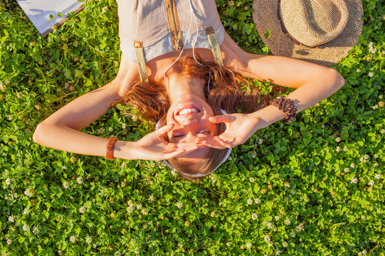 Woman Wearing Headphones Lying On Grass