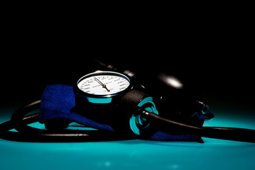 Sphygmomanometer on blue, reflective table and black background