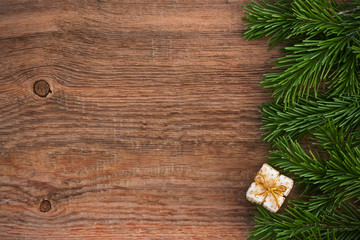Christmas card. Fir-tree branches with a gift box with a Golden