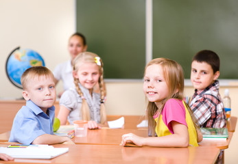 Portrait of schoolkids at workplace with teacher on background
