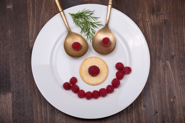 Fun food for kids - face on a plate of raspberries