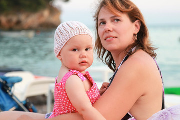 Caucasian mother with her baby girl on the sea coast