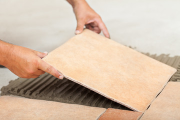 Man lays ceramic floor tiles - closeup