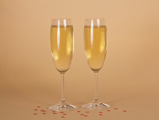 Two wine glasses of champagne on a beige background