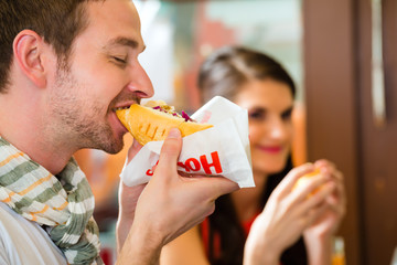 Customers eating Hotdog in fast food snack bar