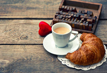 Cup of black coffee with croissant and red heart