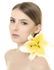 young girl with clean skin on pretty face with lily flower