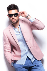 casual man fixing his sunglasses with a hand in pocket