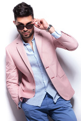 casual man with hand in pocket takes off sunglasses