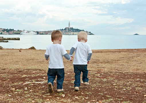Twins go by a hand on a beach in the evening. Rovinj. Croatia.