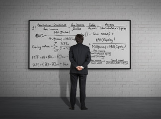 Fototapeta na wymiar Businessman standing in front of board with formulas