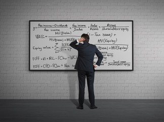 Businessman standing in front of board with formulas