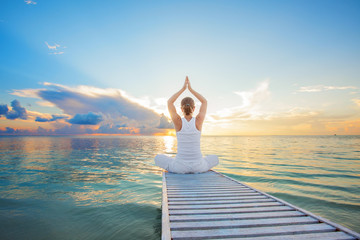 Caucasian woman practicing yoga at seashore - obrazy, fototapety, plakaty