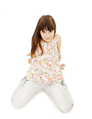 Pretty little girl sitting on the floor in jeans