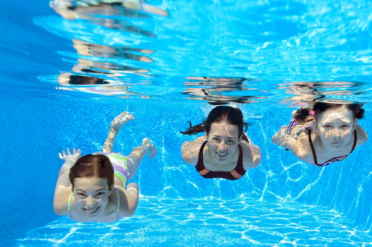 Happy family swim underwater in pool and having fun