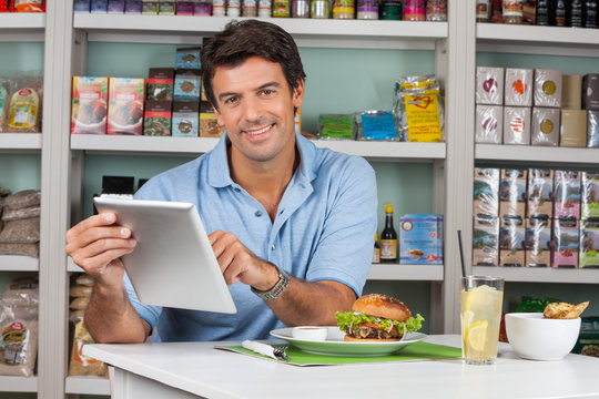 Male Customer With Snacks Using Digital Tablet In Supermarket