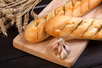 Baguettes lying on a wooden chopping board.