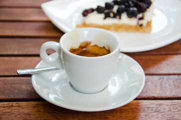 White espresso cup and a piece of blackberry cheesecake