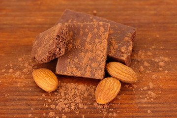 Chopped chocolate with cocoa, on wooden background