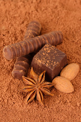 Chocolate sweets with cocoa, on brown background