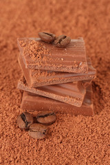 Chopped chocolate with cocoa, on brown background