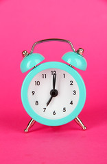 Blue alarm clock on pink background