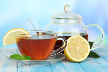 Cup of tea with lemon on table on blue background