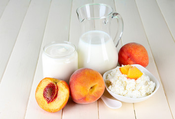 Fresh dairy products with peaches on wooden table close-up