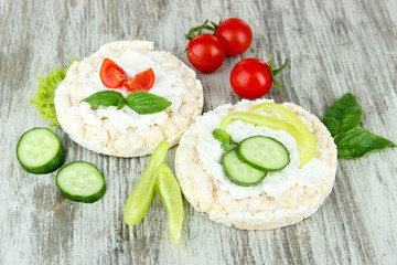 Tasty crispbreads with vegetables on wooden background