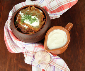 Potato pancakes in pot, on wooden background