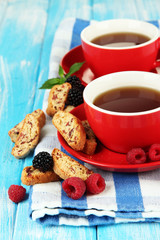 Cups of tea with cookies and berries on table close-up