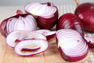 Fresh red onions on cutting board close up