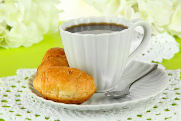 Tasty croissants and cup of coffee on table close-up