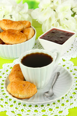 Tasty croissants and cup of coffee on table close-up