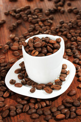 Coffee beans in cup on wooden background