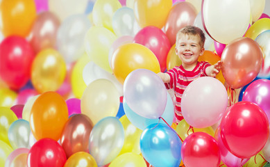 Fototapeta na wymiar Laughing boy playing among the baloons