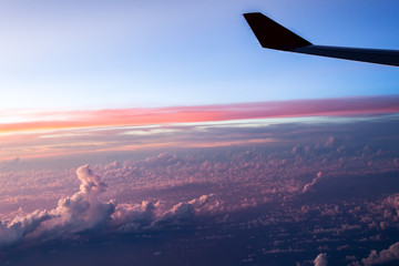 Naklejka na ściany i meble Chmury i niebo widziane przez okno samolotu na zachodzie słońca