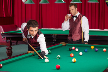 Fototapeta premium Playing pool. Two confident young men playing pool while one of