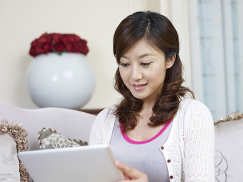 Young Asian Woman Using Tablet Computer At Home